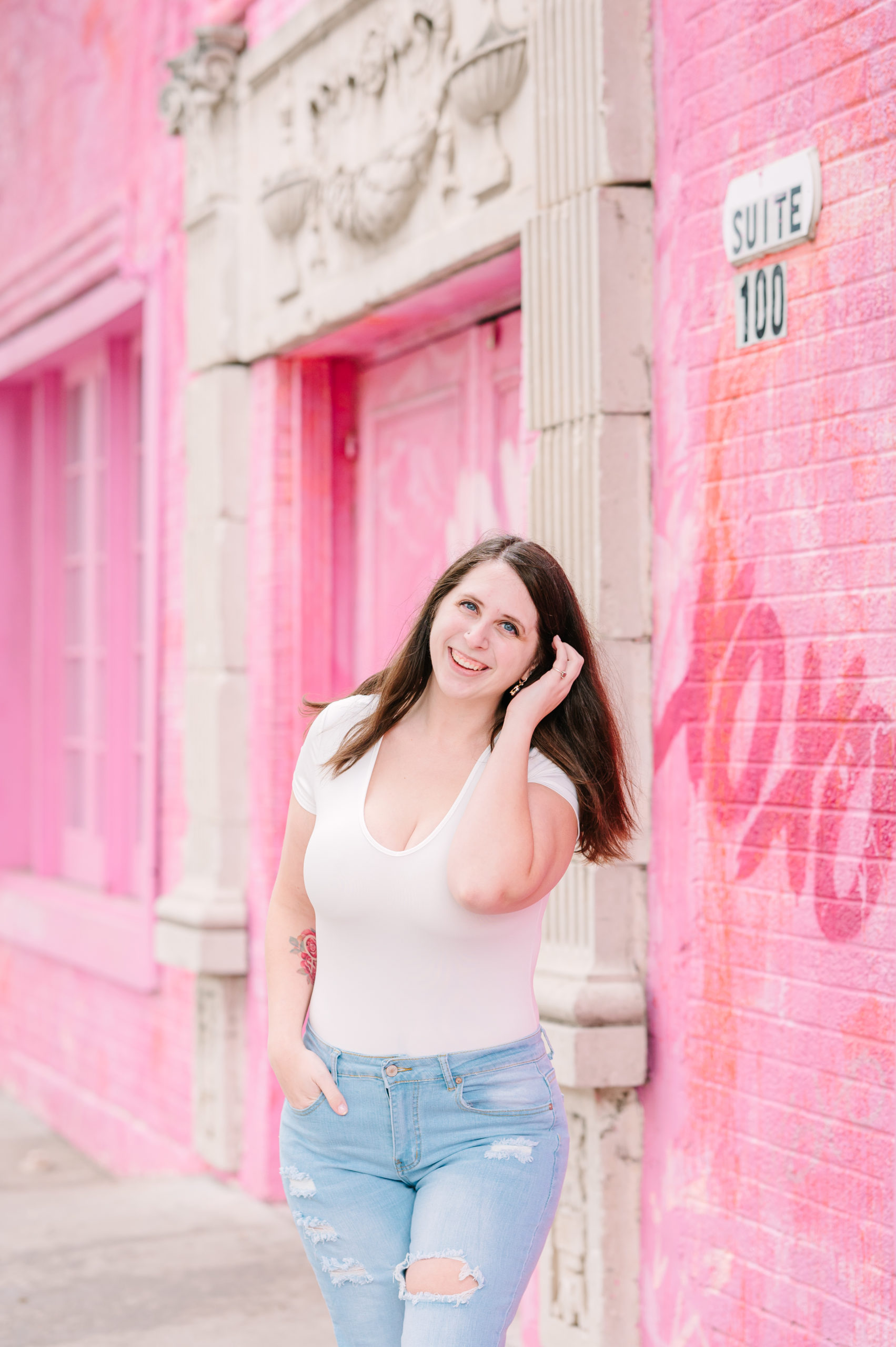 Cait Potter standing in front of a pink wall.