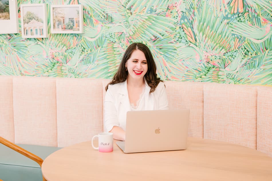 Cait Potter working on a laptop in front of palm-print wallpaper