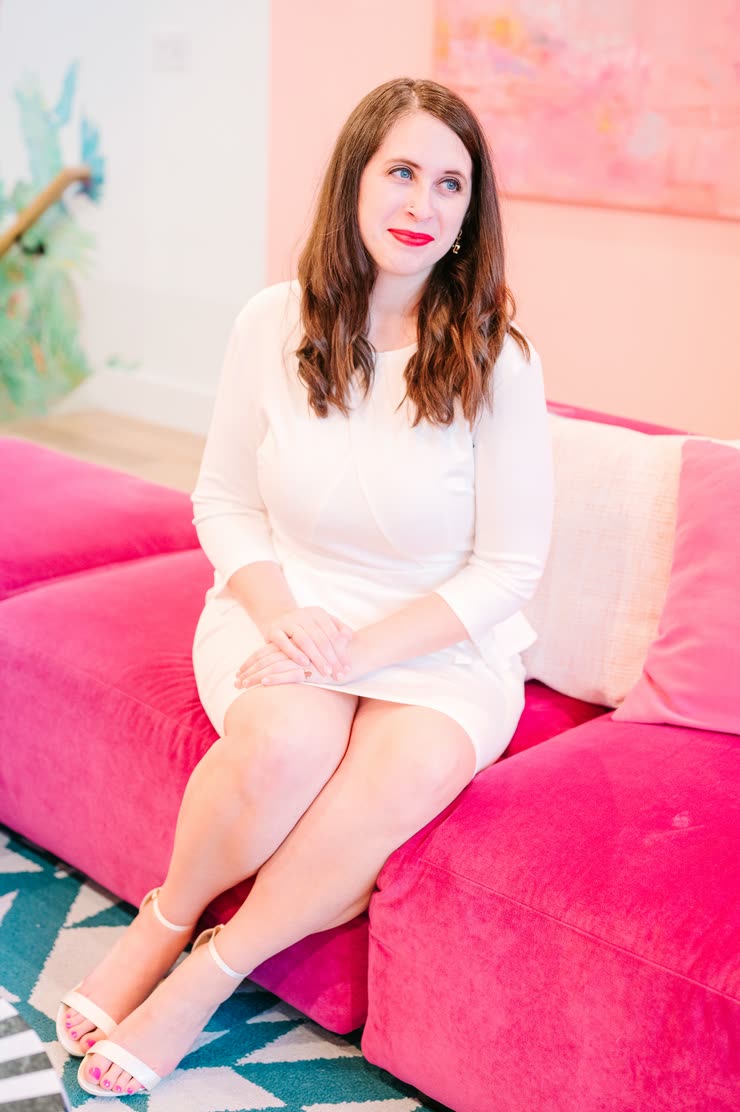 Cait Potter in a white dress on a pink sofa