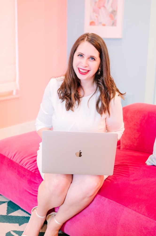 Cait Potter working on her laptop on a pink couch