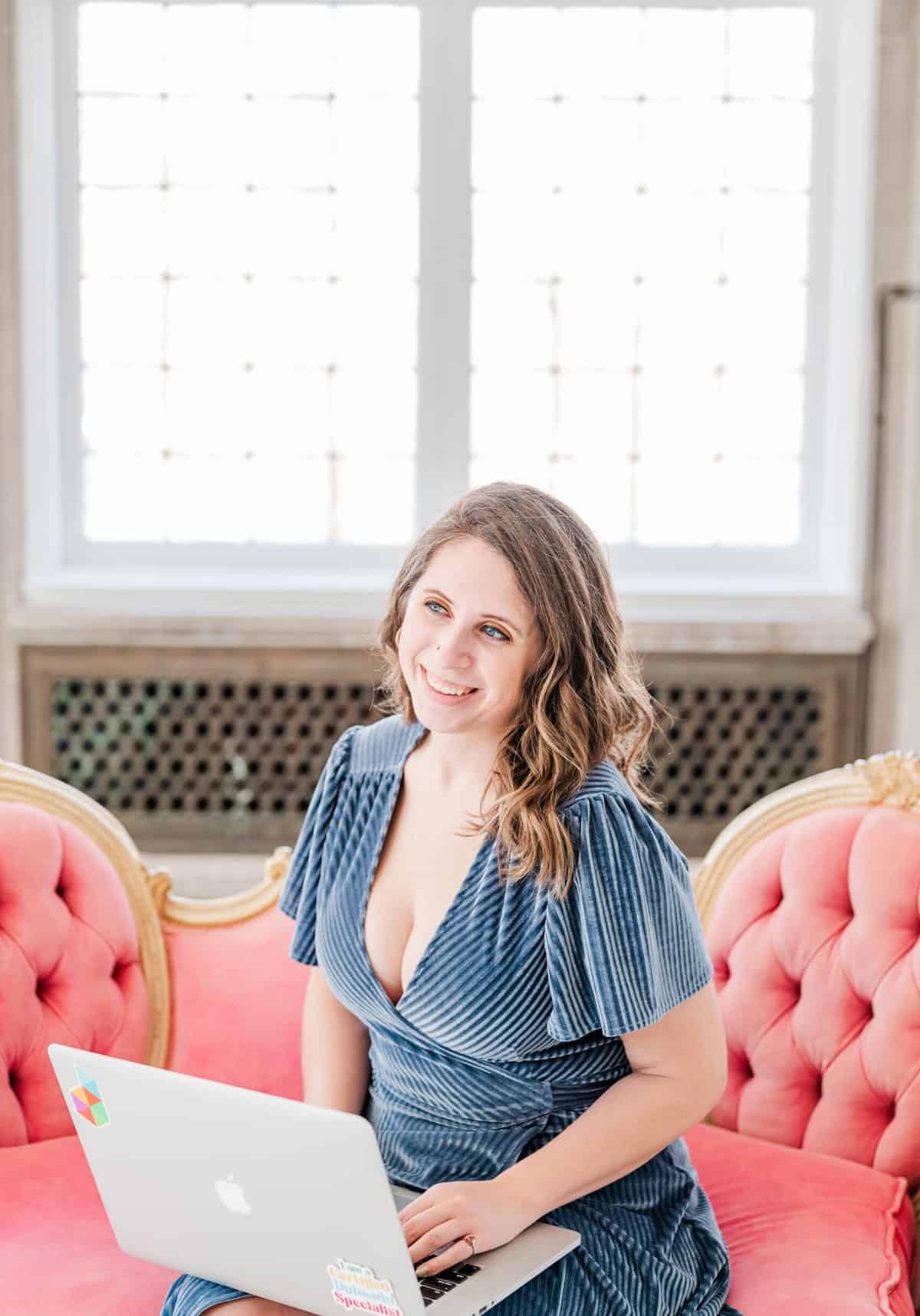Cait Potter with her laptop on a pink sofa