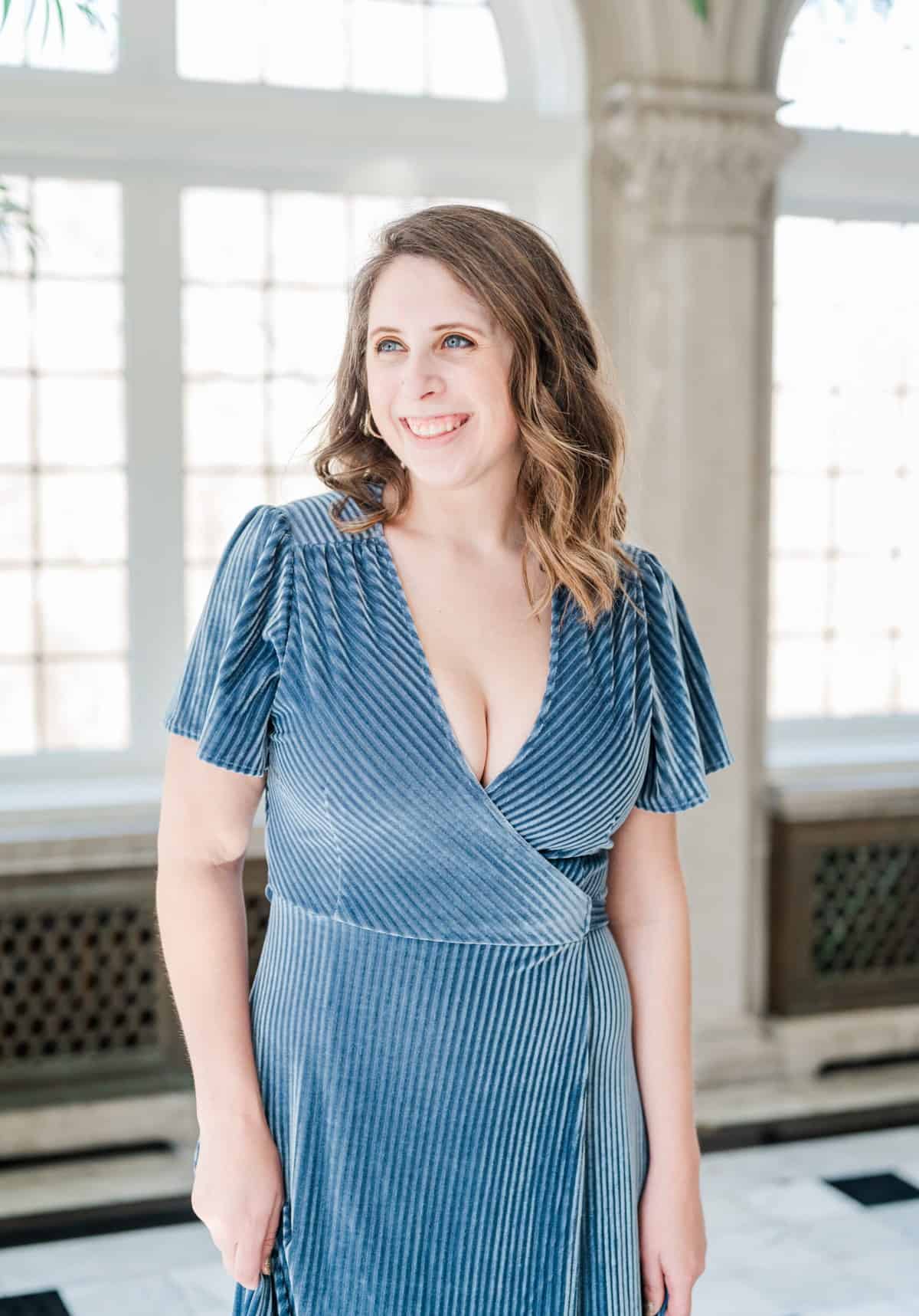 Cait Potter in a blue dress by a sunny window